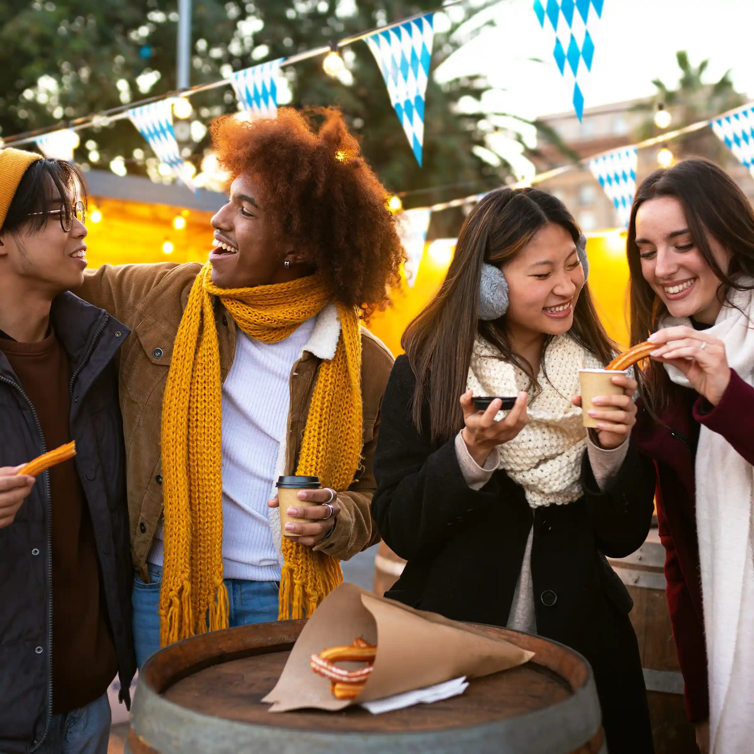 Grupa znajomych jedzących churros na jarmarku ulicznym