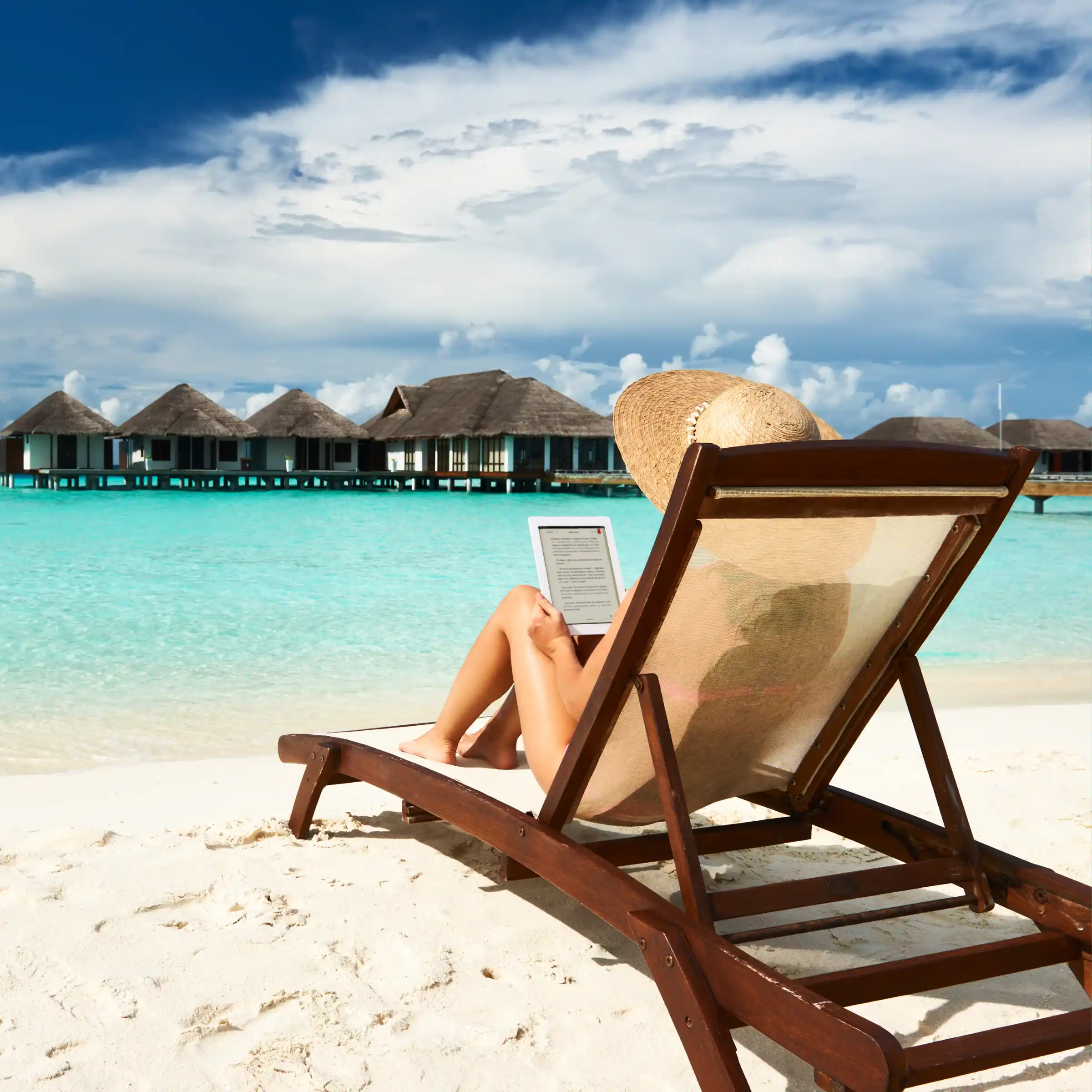 Kobieta z czytnikiem książek na leżaku